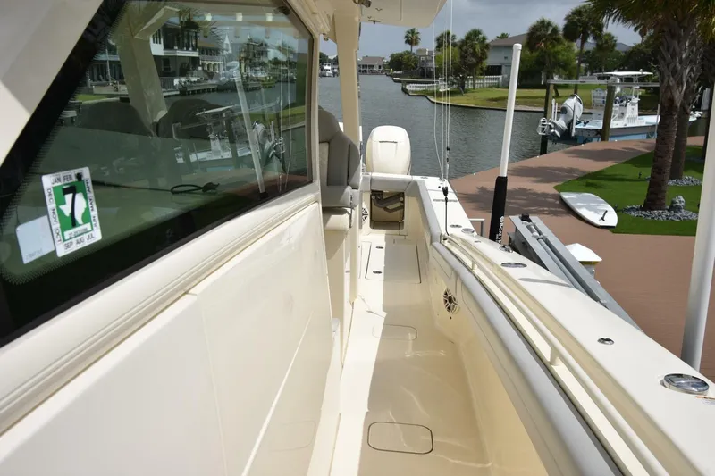  Yacht Photos Pics 2022 Scout 425 LXF boat docked by a scenic waterfront with palm trees.