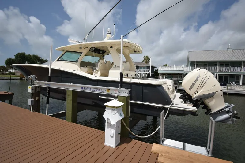  Yacht Photos Pics 2022 Scout 425 LXF boat on lift, docked by waterfront homes.