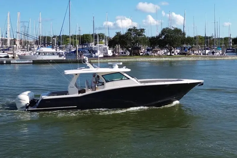  Yacht Photos Pics 2022 Scout 425 LXF boat cruising in a marina with sailboats in the background.