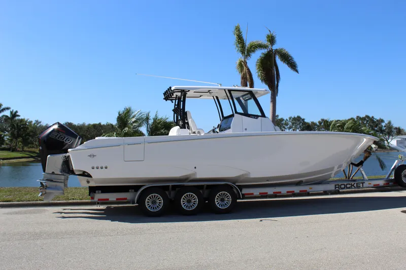  Yacht Photos Pics 2024 Fountain 32 NX boat on trailer, parked near palm trees and water.