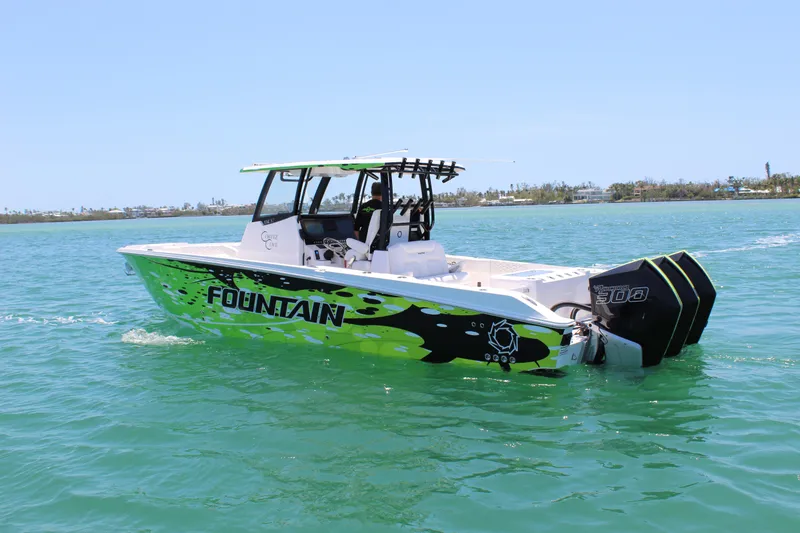 Yacht Photos Pics 2024 Fountain 32 NX boat with vibrant graphics cruising on clear blue water.