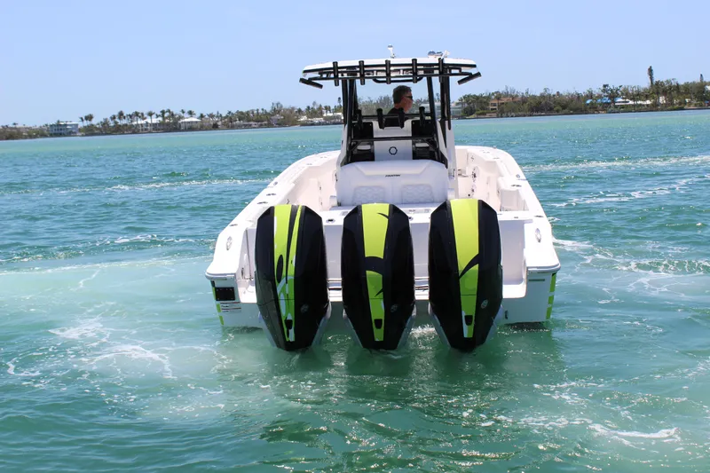 Yacht Photos Pics 2024 Fountain 32 NX boat with triple outboard engines cruising on clear blue water.