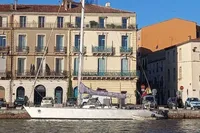Sailboat "Cape Codder Coder Withbread 57" docked by historic European buildings, 1985 model.