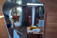 Interior of 1985 Cape Codder Coder Withbread 57 sailboat, featuring wooden furnishings and striped seating.
