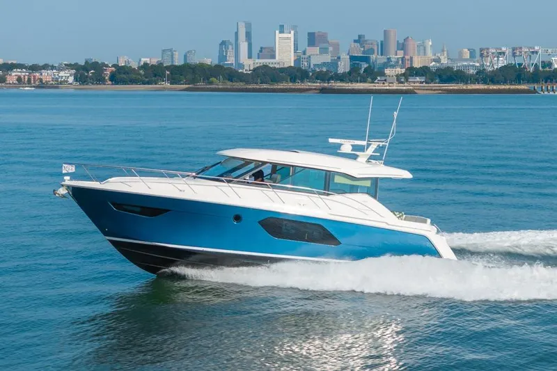 Bacchus Yacht Photos Pics 2022 Tiara Yachts Coupe cruising on water with city skyline in background.