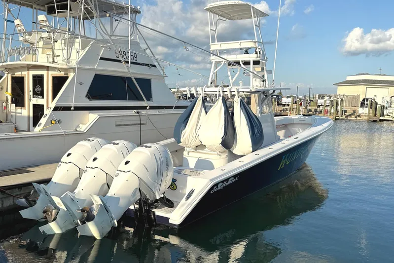 Huntress Yacht Photos Pics 2007 SeaHunter 40 boat docked with triple outboard engines, clear sky background.