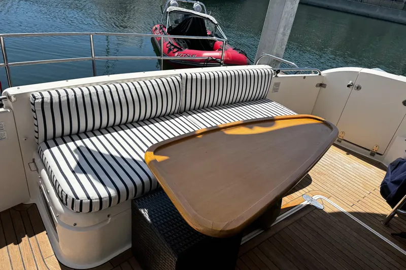 My Way Yacht Photos Pics Outdoor seating area on 2001 Fairline 55 yacht with striped cushions and wooden table.