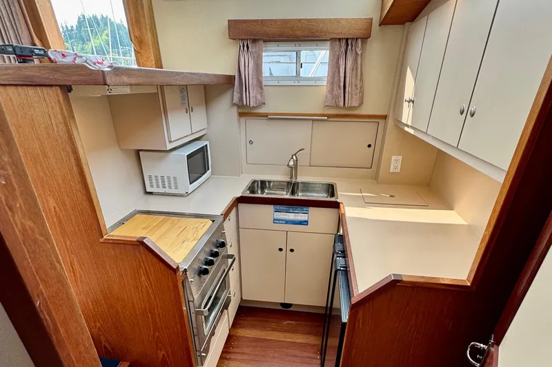 Rosie Mclane Yacht Photos Pics Compact kitchen in a 2006 Westcoast Sedan, featuring a sink, stove, and microwave.