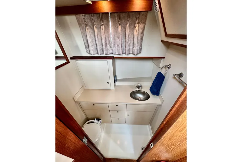 Rosie Mclane Yacht Photos Pics Compact bathroom in 2006 Westcoast Sedan, featuring sink, storage, and blue towel.