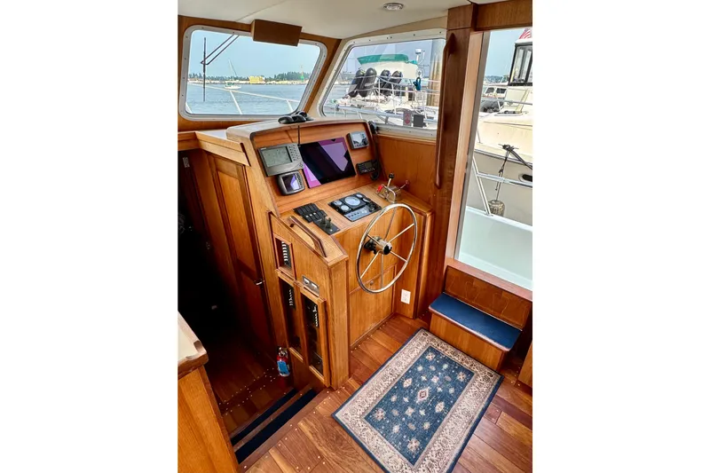 Rosie Mclane Yacht Photos Pics Wooden boat interior with steering wheel, navigation equipment, and a patterned rug.