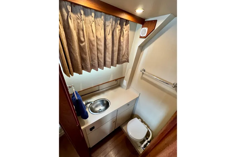 Rosie Mclane Yacht Photos Pics Compact bathroom in a 2006 Westcoast Sedan, featuring sink, toilet, and curtain.
