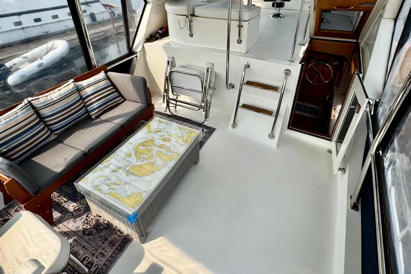 Rosie Mclane Yacht Photos Pics Luxurious yacht interior with seating, nautical map table, and ladder, showcasing elegance and functionality.