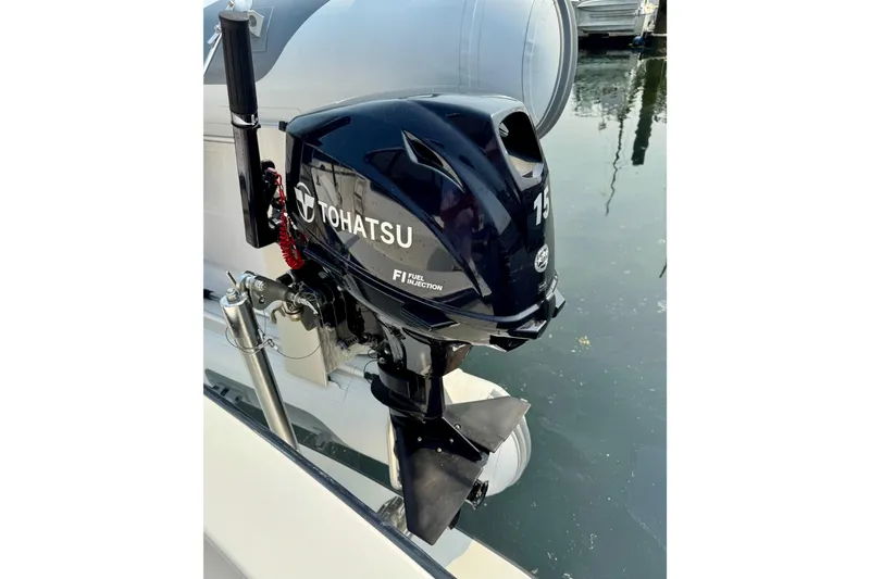 Rosie Mclane Yacht Photos Pics Tohatsu outboard motor on a boat, reflecting on calm water.