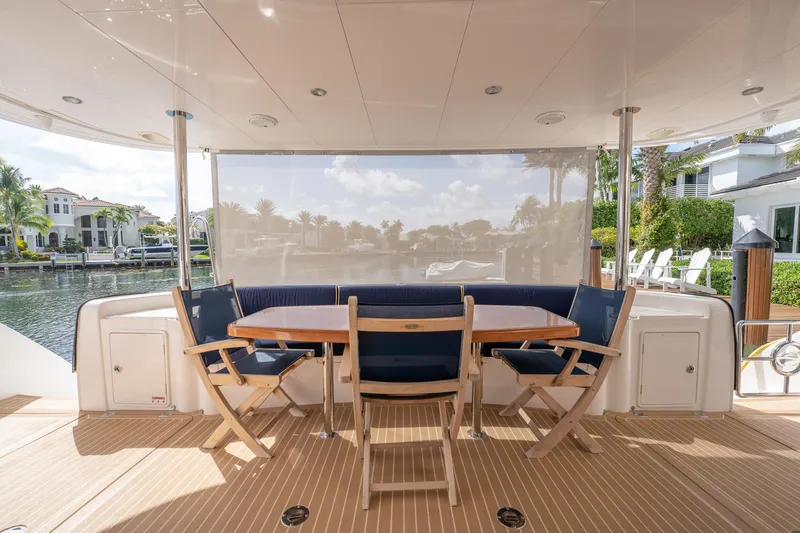 Passion Yacht Photos Pics Outdoor seating area on 2019 Horizon PC52 yacht, featuring wooden table and chairs by the water.