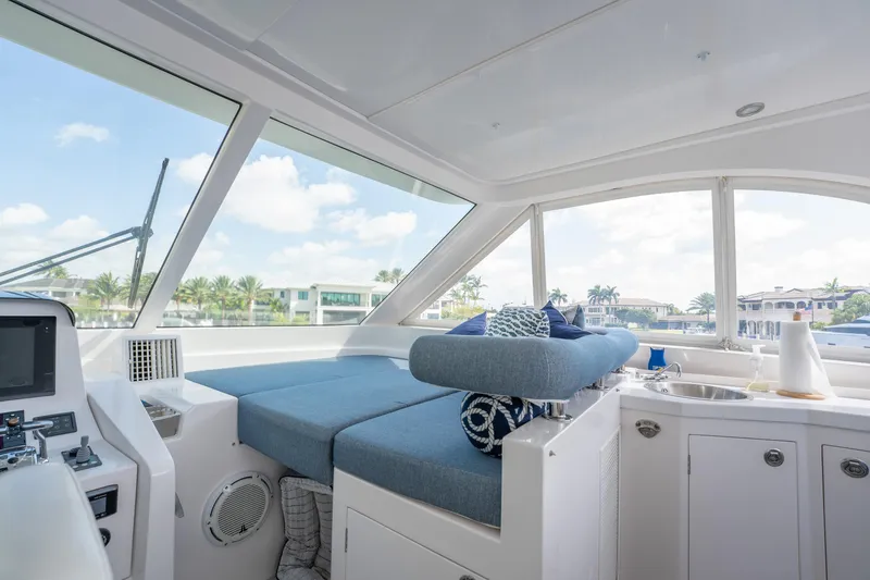 Passion Yacht Photos Pics Interior of 2019 Horizon PC52 yacht with blue seating, windows, and kitchenette.