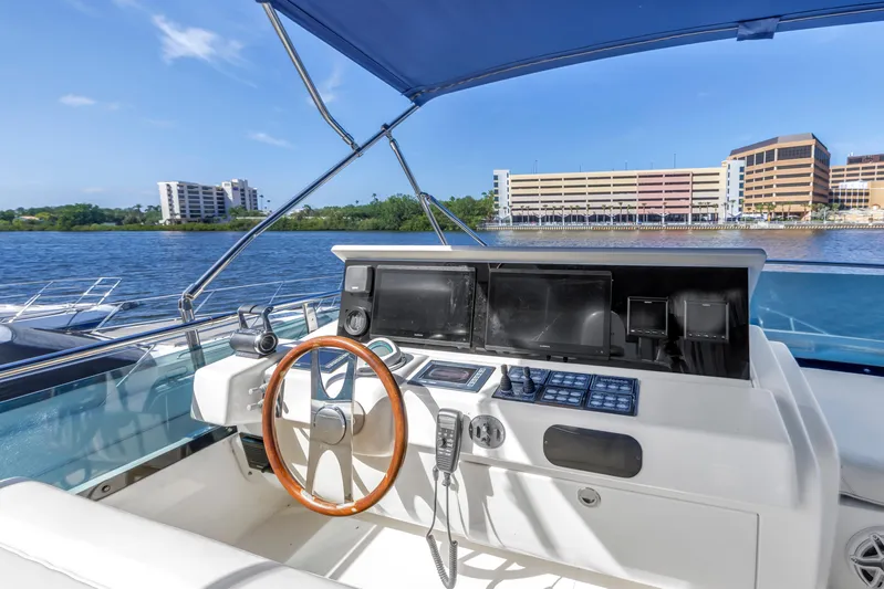 Solaris Yacht Photos Pics 2009 Uniesse 65 MY yacht helm with wooden steering wheel, overlooking waterfront buildings.