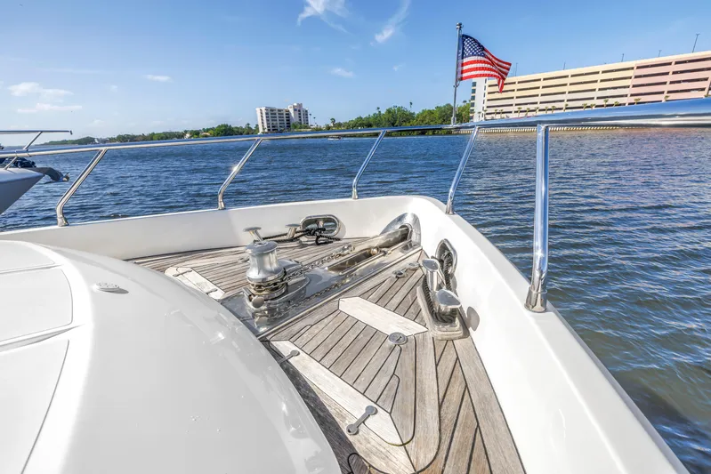 Solaris Yacht Photos Pics 2009 Uniesse 65 MY yacht deck with American flag, docked near waterfront buildings.