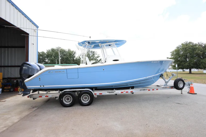  Yacht Photos Pics 2022 Cobia 301 Center Console boat on trailer, parked outside a building.