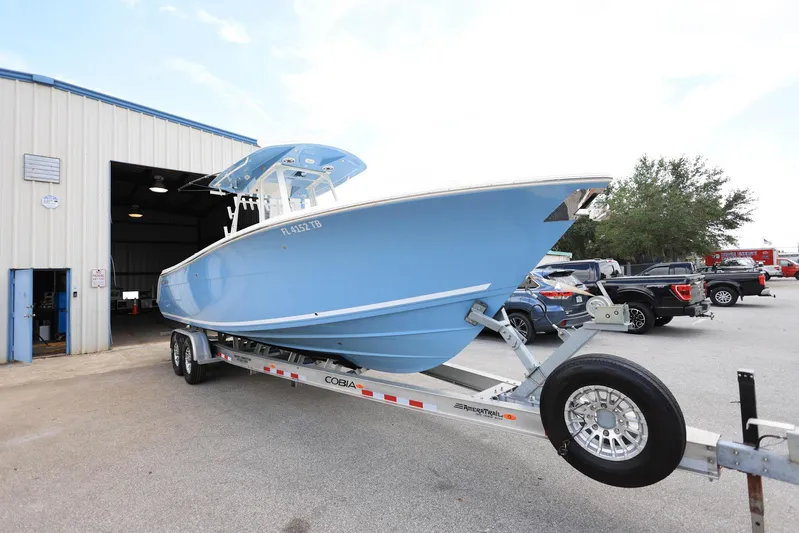  Yacht Photos Pics 2022 Cobia 301 Center Console boat on trailer outside a warehouse.