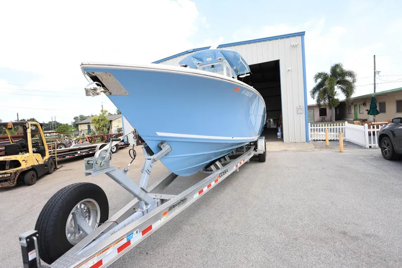  Yacht Photos Pics 2022 Cobia 301 Center Console boat on trailer outside a warehouse.
