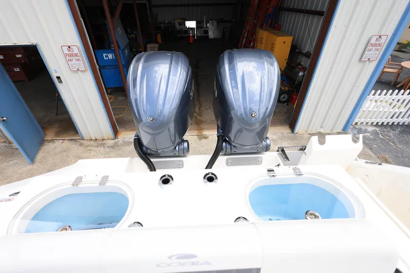  Yacht Photos Pics 2022 Cobia 301 Center Console with dual outboard engines in a storage facility.