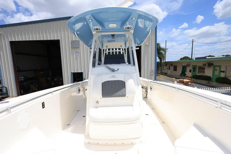  Yacht Photos Pics 2022 Cobia 301 Center Console boat with blue canopy, docked near industrial buildings.
