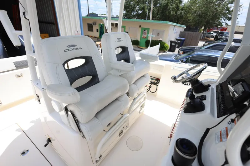 Yacht Photos Pics 2022 Cobia 301 Center Console boat with dual white captain's chairs and control panel.