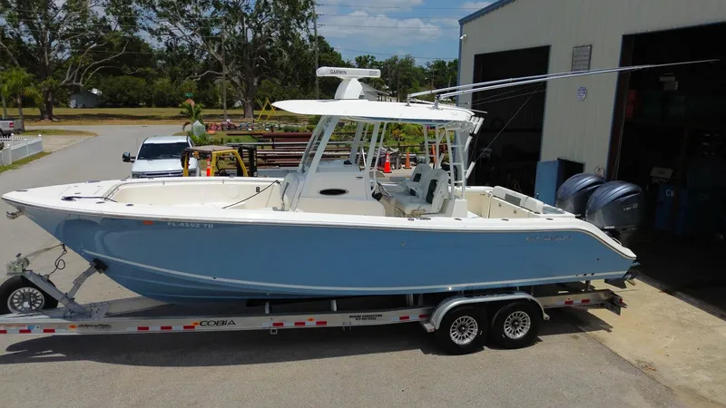  Yacht Photos Pics 2022 Cobia 301 Center Console boat on trailer outside a garage.
