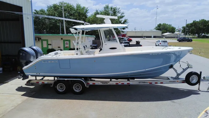  Yacht Photos Pics 2022 Cobia 301 Center Console boat on trailer, parked outdoors.