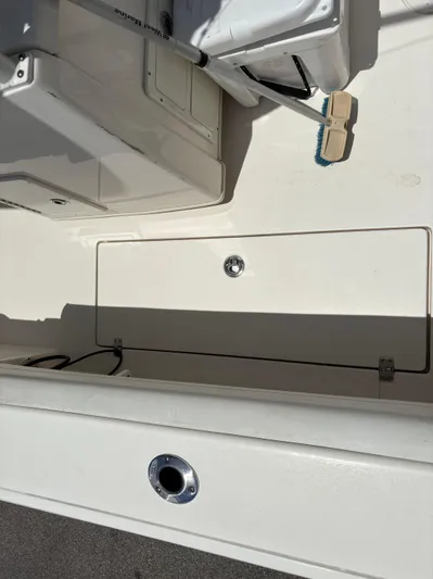  Yacht Photos Pics 2022 Cobia 301 Center Console boat deck with storage compartment and cleaning brush.