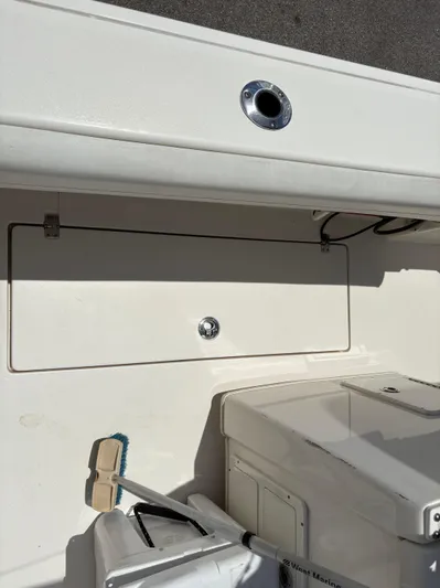  Yacht Photos Pics 2022 Cobia 301 Center Console boat interior with storage compartment and cleaning brush.