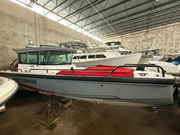 Underestimated Yacht Photos Pics 2021 Axopar 28 CABIN boat in storage, featuring a sleek design and red cover.