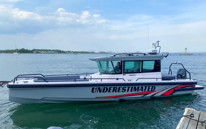 Underestimated Yacht Photos Pics 2021 Axopar 28 CABIN boat on water, labeled "Underestimated," with scenic background.