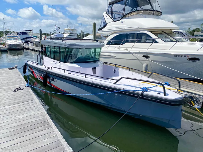 Underestimated Yacht Photos Pics 2021 Axopar 28 CABIN boat docked at a marina under a partly cloudy sky.