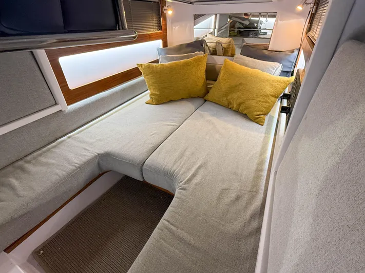 Underestimated Yacht Photos Pics 2021 Axopar 28 CABIN interior with cozy seating and yellow cushions.