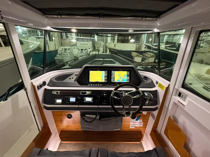 Underestimated Yacht Photos Pics Interior view of 2021 Axopar 28 CABIN boat cockpit with navigation screens and steering wheel.