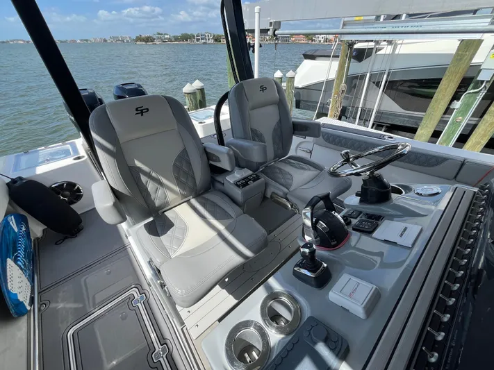  Yacht Photos Pics 2022 Seapro 320 DLX boat interior with dual seats and control panel, docked by the water.
