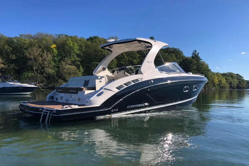  Yacht Photos Pics 2017 Chaparral 337 SSX boat on calm water, surrounded by lush greenery.