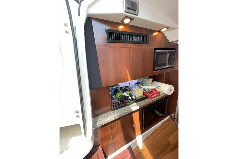  Yacht Photos Pics 2017 Chaparral 337 SSX interior with wooden cabinetry, microwave, and countertop items.