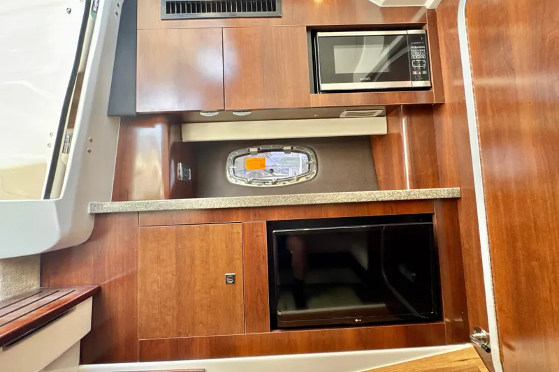  Yacht Photos Pics 2017 Chaparral 337 SSX interior with microwave, wooden cabinetry, and small window.