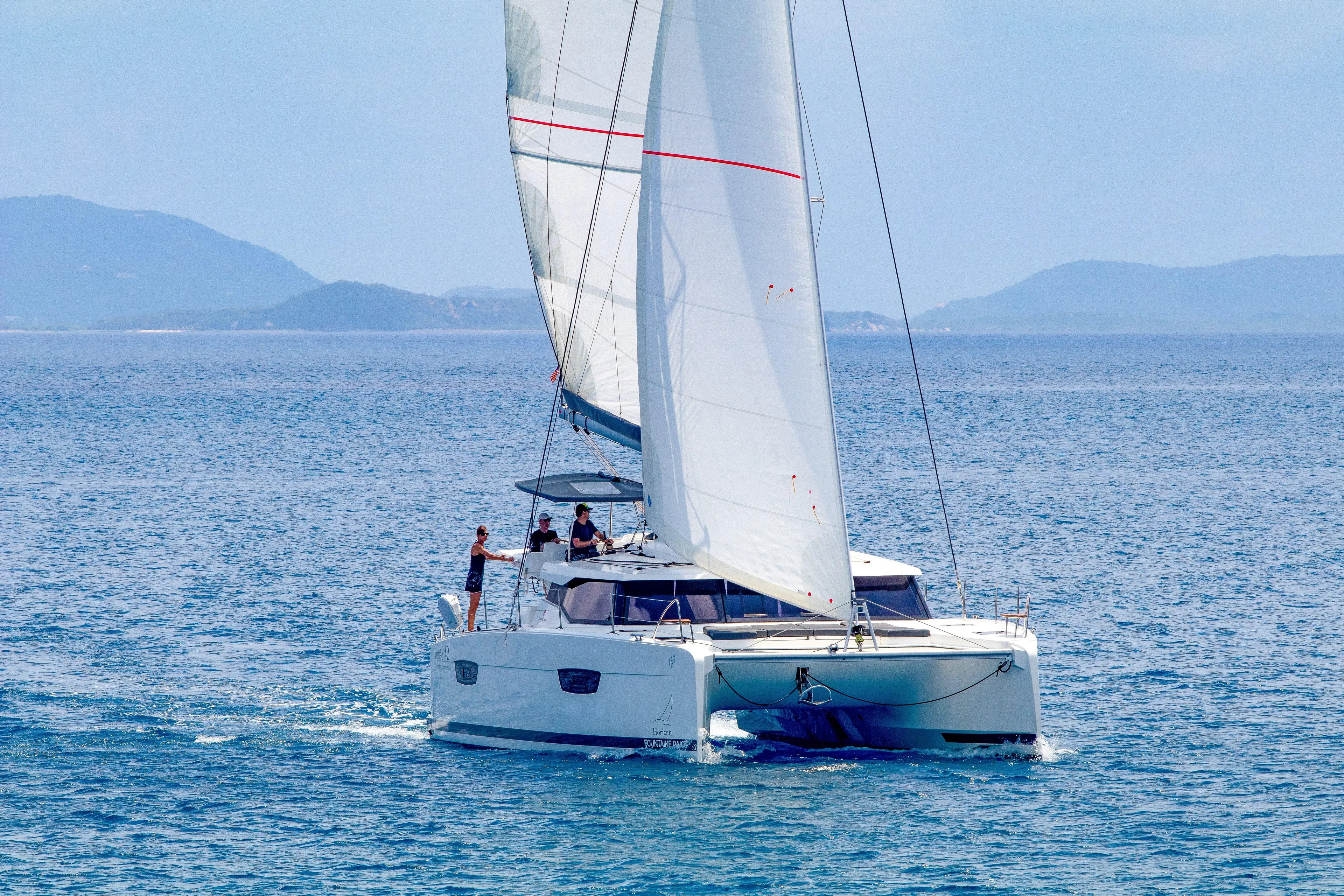 Pegasus Yacht Photos Pics 2022 Fountaine Pajot Astrea 42 catamaran sailing on open sea with distant hills.