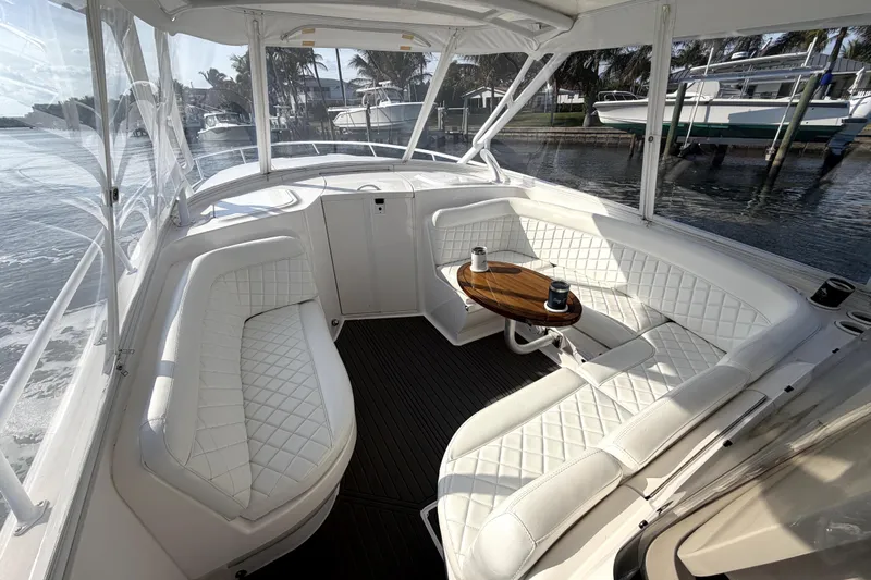  Yacht Photos Pics 2014 Intrepid 400 Cuddy interior with white seating and wooden table, docked by the water.