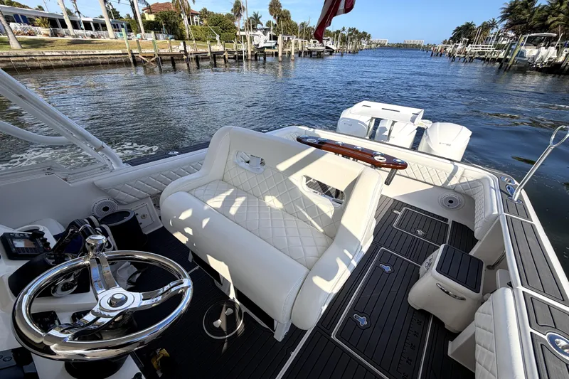  Yacht Photos Pics 2014 Intrepid 400 Cuddy boat interior with steering wheel and seating, docked by waterfront homes.