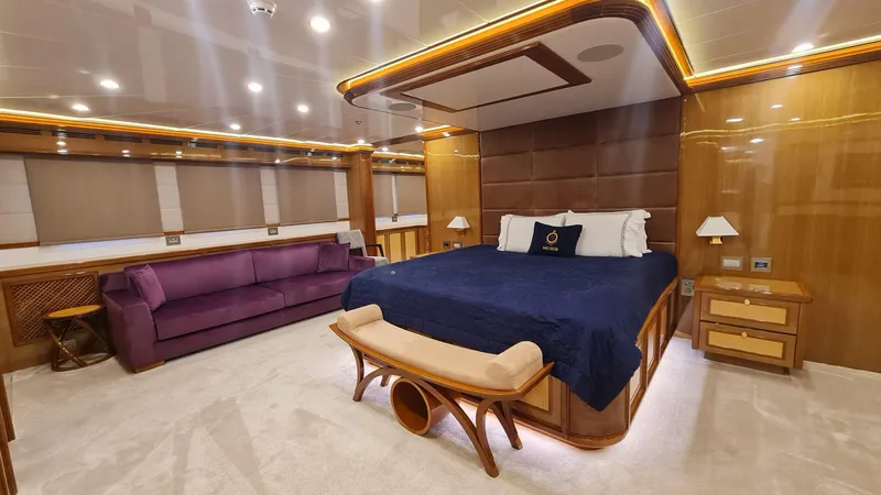 Yacht Photos Pics Luxurious yacht bedroom with elegant wood finishes, plush purple sofa, and ambient lighting.