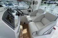 Luxury yacht cockpit with dual white seats, wooden flooring, and control panel. Trader 42, 2007 model.