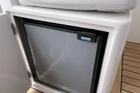 Compact refrigerator on a 2007 Trader 42 boat with cushioned seating above.