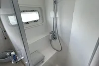 Compact bathroom with shower in 2007 Trader 42 yacht, featuring modern fixtures and window.