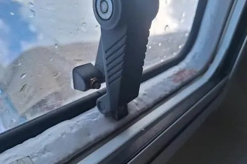 Bermuda Yacht Photos Pics Window latch on 2017 Dufour 412 Grand Large yacht, with raindrops visible outside.