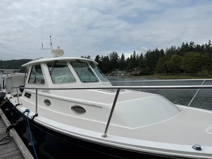Skookum Yacht Photos Pics 2009 Back Cove 29 boat docked by a scenic forested shoreline.