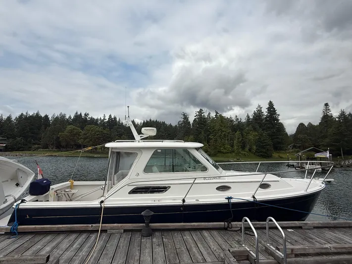 Skookum Yacht Photos Pics 2009 Back Cove 29 boat docked by a scenic forested shoreline.